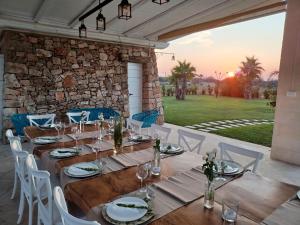 comedor con mesa, sillas y pared de piedra en Trullo TerraNostra villa con piscina Torre San Giovanni, en Ugento