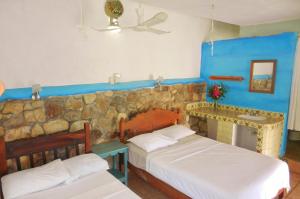 a bedroom with two beds and a stone wall at Altamira Mazunte in Mazunte