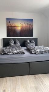 ein Bett mit zwei Kissen und einem Gemälde an der Wand in der Unterkunft Modernes 2 Zimmer Appartment in Göttingen