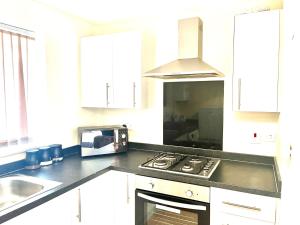 a kitchen with a stove top oven and a microwave at Lt Properties Studio apartment Ground floor 3 in Luton