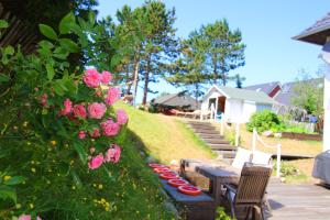 einen Garten mit einem Holztisch und rosa Rosen in der Unterkunft GROßE-WILDE-BETTEN in Wittdün