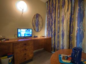 a room with a desk with a television on a dresser at Hotel Leonardo Da Vinci in Limone sul Garda