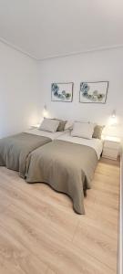 two beds in a white room with wooden floors at Cozy White Home in Getxo in Getxo