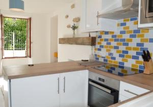 a kitchen with white cabinets and a colorful tile wall at Chez Claire in Excideuil