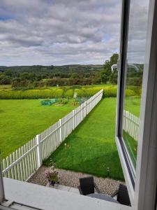 een raam met uitzicht op een tuin met een wit hek bij Doonan Breeze in Donegal
