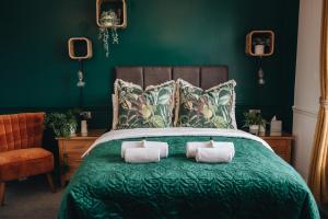 a green bedroom with a green bed with two pillows at Cloves Boutique Bed & Breakfast in Cleethorpes