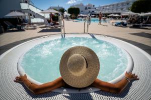 a woman in a straw hat laying in a pool at Hotel Lanzarote Village in Puerto del Carmen