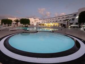 a large swimming pool in a resort at night at Hotel Lanzarote Village in Puerto del Carmen