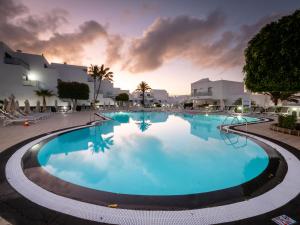 a large swimming pool in a resort at dusk at Hotel Lanzarote Village in Puerto del Carmen
