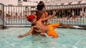a man and woman playing in a swimming pool at Hotel Lanzarote Village in Puerto del Carmen