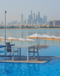 a table with chairs and umbrellas in a pool at C Central Hotel and Resort The Palm in Dubai