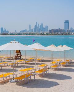 a beach area with umbrellas and chairs at C Central Hotel and Resort The Palm in Dubai