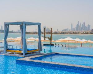 a swimming pool with chairs and umbrellas in the water at C Central Hotel and Resort The Palm in Dubai