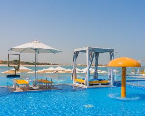 a swimming pool with chairs and umbrellas in the water at C Central Hotel and Resort The Palm in Dubai