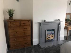 a bedroom with a fireplace next to a dresser at Cosy Haven in South Shields