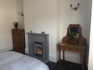 a bedroom with a bed and a fireplace and a dresser at Cosy Haven in South Shields