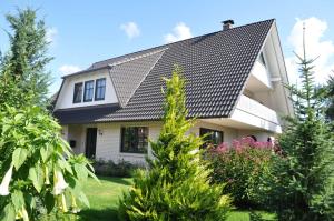 ein Haus mit schwarzem Dach und einigen Bäumen in der Unterkunft Schippers Butz strandnah mit Whirpool in Ostseebad Karlshagen