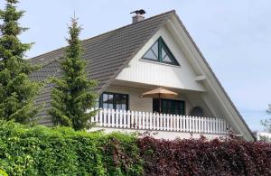 a house with a white fence and an umbrella at Schippers Butz strandnah mit Whirpool in Ostseebad Karlshagen