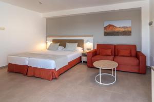 a bedroom with a bed and a red couch at Hotel Lanzarote Village in Puerto del Carmen