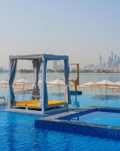 a swimming pool with chairs and umbrellas on the water at C Central Hotel and Resort The Palm in Dubai