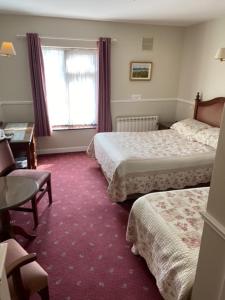 una camera d'albergo con due letti e una scrivania di Monaghans Harbour Hotel a Naas