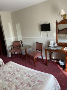 Habitación de hotel con cama, mesa y sillas en Monaghans Harbour Hotel, en Naas