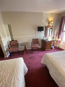 um quarto de hotel com duas camas e uma mesa e cadeiras em Monaghans Harbour Hotel em Naas