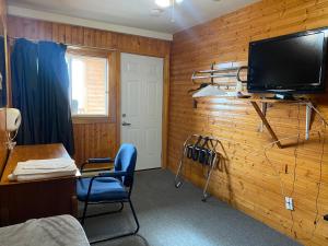 Habitación con pared de madera y TV de pantalla plana. en Hillcrest Motel, en Saint John