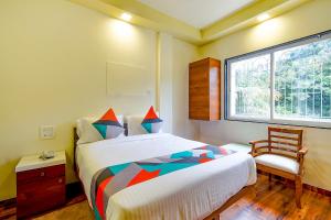 a bedroom with a bed and a chair and a window at FabHotel Nandanvan in Pune