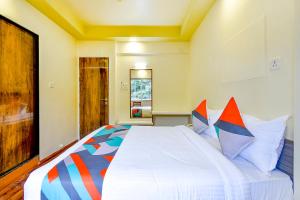 a bedroom with a large white bed with colorful pillows at FabHotel Nandanvan in Pune