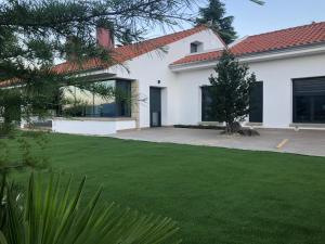 una casa blanca con un patio con césped verde en Apartamentos Rurales La Gloria de Yuste, en Jaraíz de la Vera