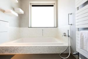 a bath tub in a bathroom with a window at Droomvakanties Egmond Appartement van Speijk in Egmond aan Zee +11 photos