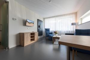 a living room with a table and blue chairs at Droomvakanties Egmond Appartement van Speijk in Egmond aan Zee