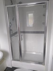 a shower with a glass door in a bathroom at Stylish Private Double Room w/ensuite in London