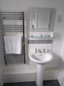 Baño blanco con lavabo y espejo en Stylish Private Double Room w/ensuite en Londres