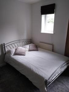 a bedroom with a white bed with two pillows on it at Stylish Private Double Room w/ensuite in London