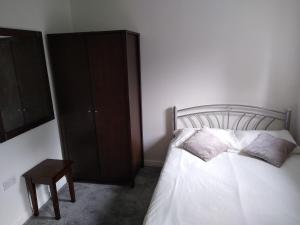 a bedroom with a white bed and a wooden cabinet at Stylish Private Double Room w/ensuite in London