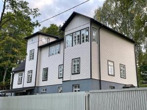 une grande maison blanche avec une clôture devant elle dans l'établissement Pühajärve residents, à Otepää