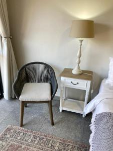 a bedroom with a chair and a lamp next to a bed at Tidor Garden Cottage in Bloemfontein