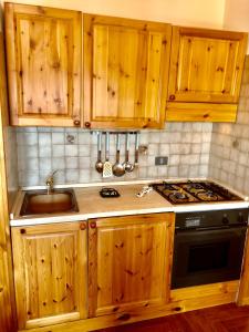 a kitchen with wooden cabinets and a stove and a sink at Casa serenaurora in Castel di Sangro