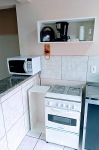 a kitchen with a white stove and a microwave at Residencial JOED 3 in Dourados