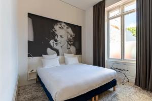 a bedroom with a bed with a picture of a woman on a phone at Hôtel François 1er in La Rochelle