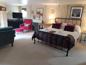 a bedroom with a bed and a chair and a television at Huberts, West End Farm, Fosse Lane, Poolbridge Road, Blackford, Wedmore in Wedmore