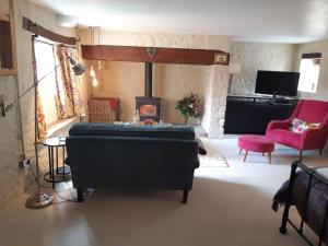 een woonkamer met een bank en een open haard bij Huberts, West End Farm, Fosse Lane, Poolbridge Road, Blackford, Wedmore in Wedmore