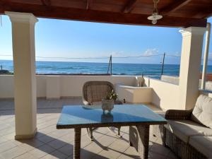 a patio with a table and a view of the ocean at Acharavi, villa next to the beach in Acharavi