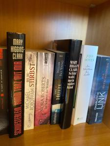 a row of books sitting on a book shelf at Andrea's Ferienwohnung in Brietlingen