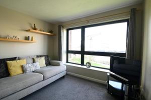 a living room with a couch and a large window at SEC/ Hydro Two Bed Flat With Free parking and Great View in Glasgow