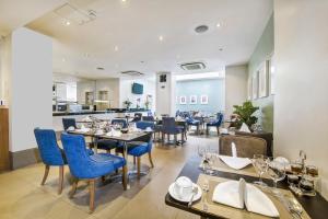 un restaurante con sillas y mesas azules en una habitación en Gem Langham Court Hotel en Londres