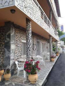 a building with chairs and tables and flowers in front of it at Miltos rooms in Leptokarya