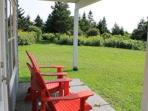 twee rode stoelen op de veranda van een huis bij Seawind Landing Country Inn in Larrys River